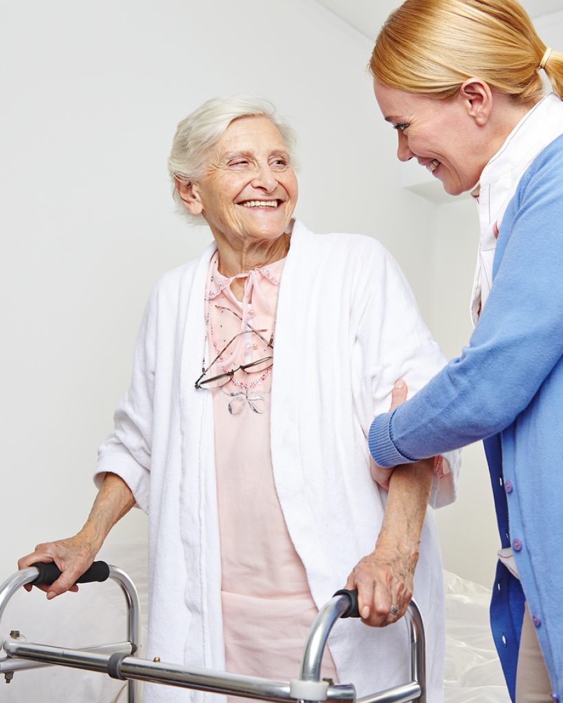Geriatric nurse helping senior citizen woman with walker